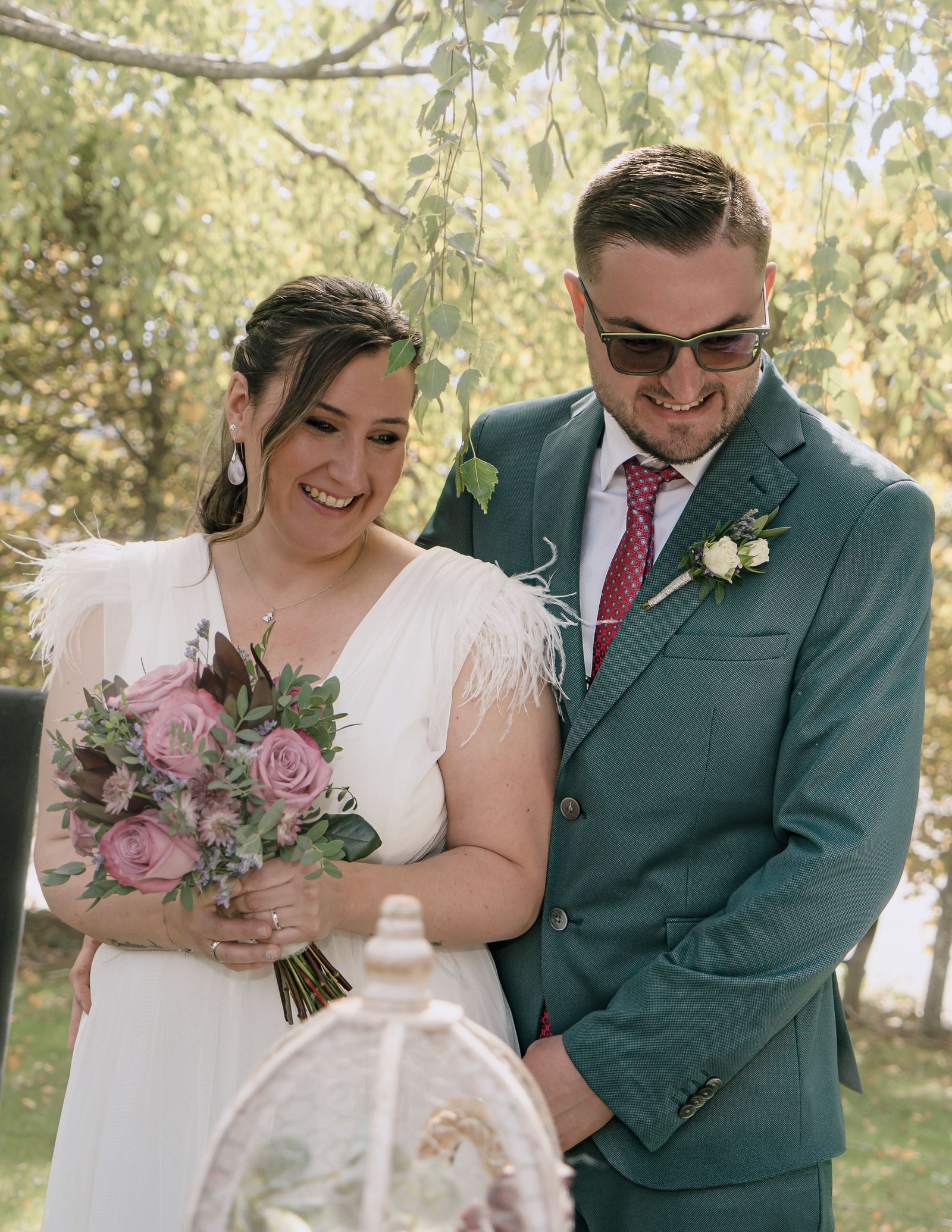 Pareja de recién casados junto a su ramo bajo los árboles