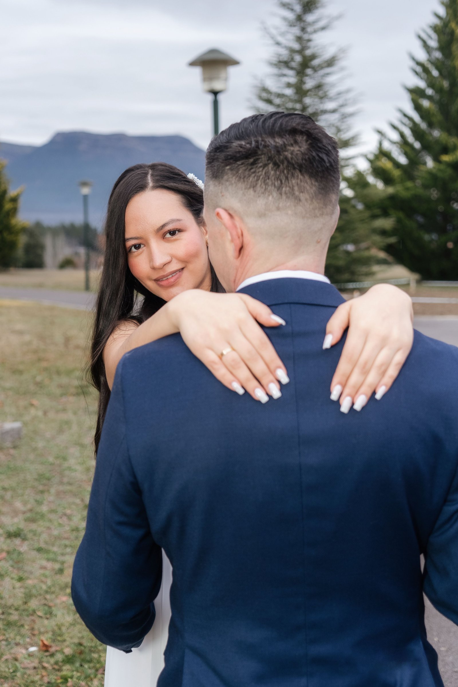 Novia mirando a cámara mientras abraza a su pareja