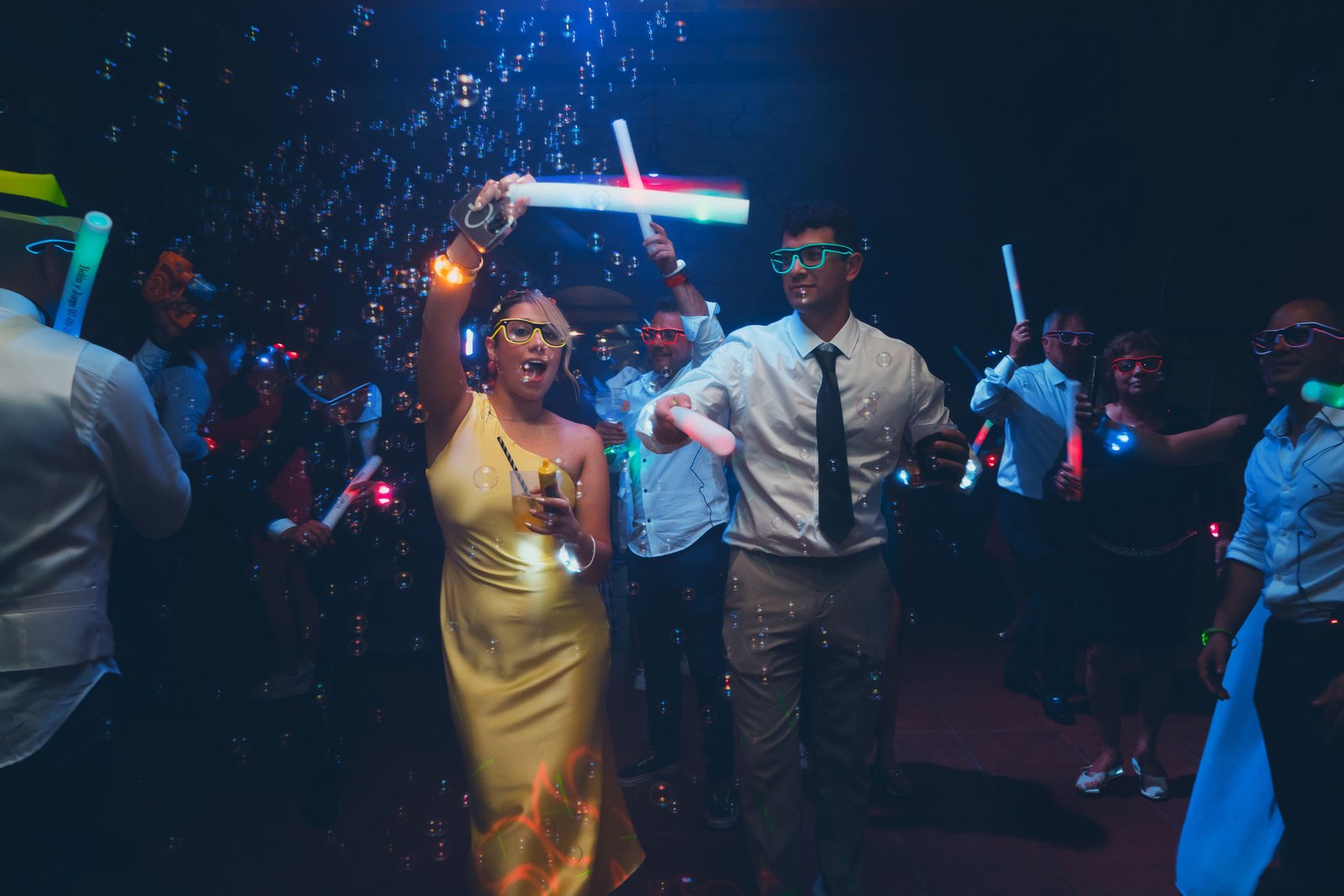 Celebración de boda bajo luces de neón y burbujas