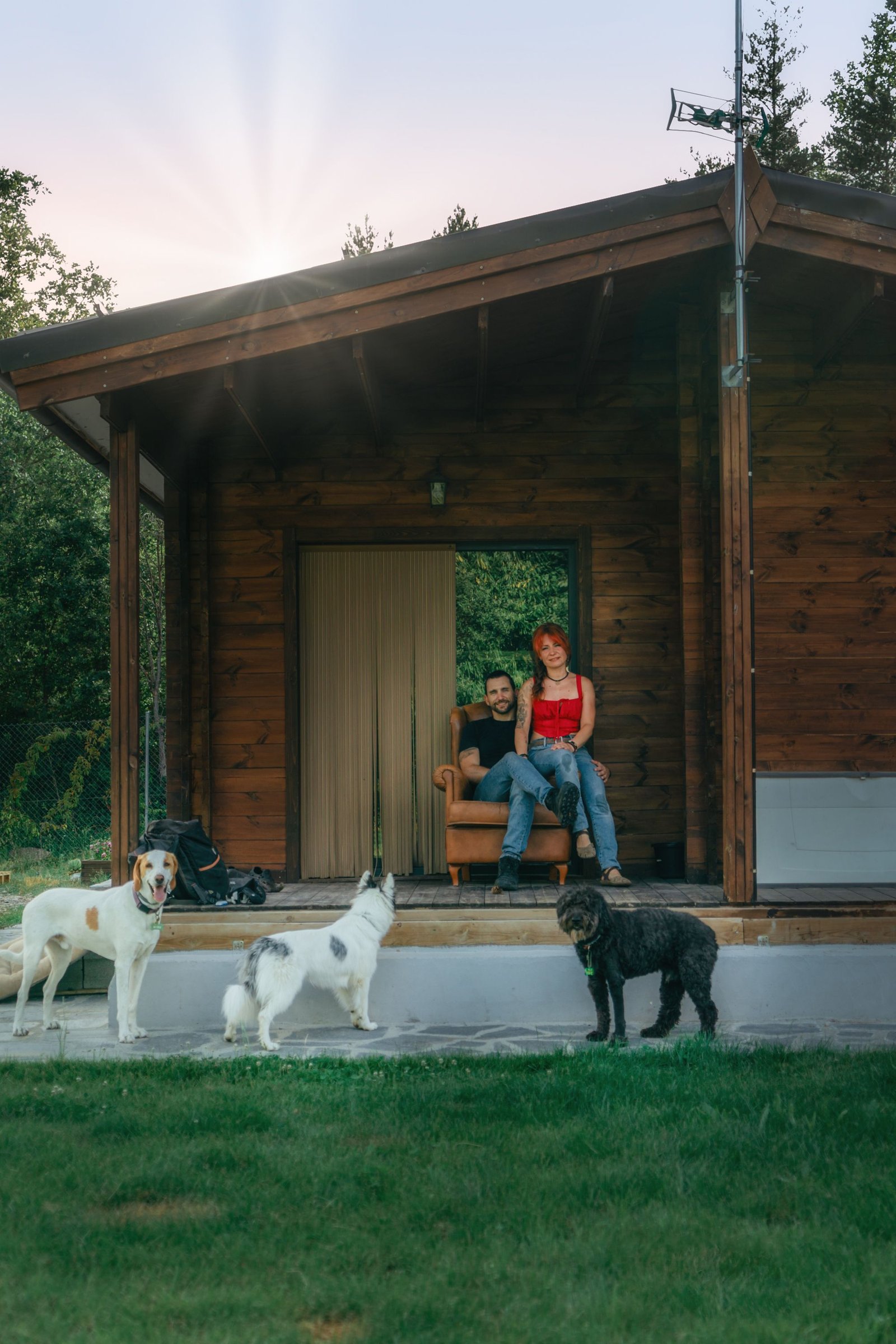 Familia con sus perros frente a una cabaña de madera